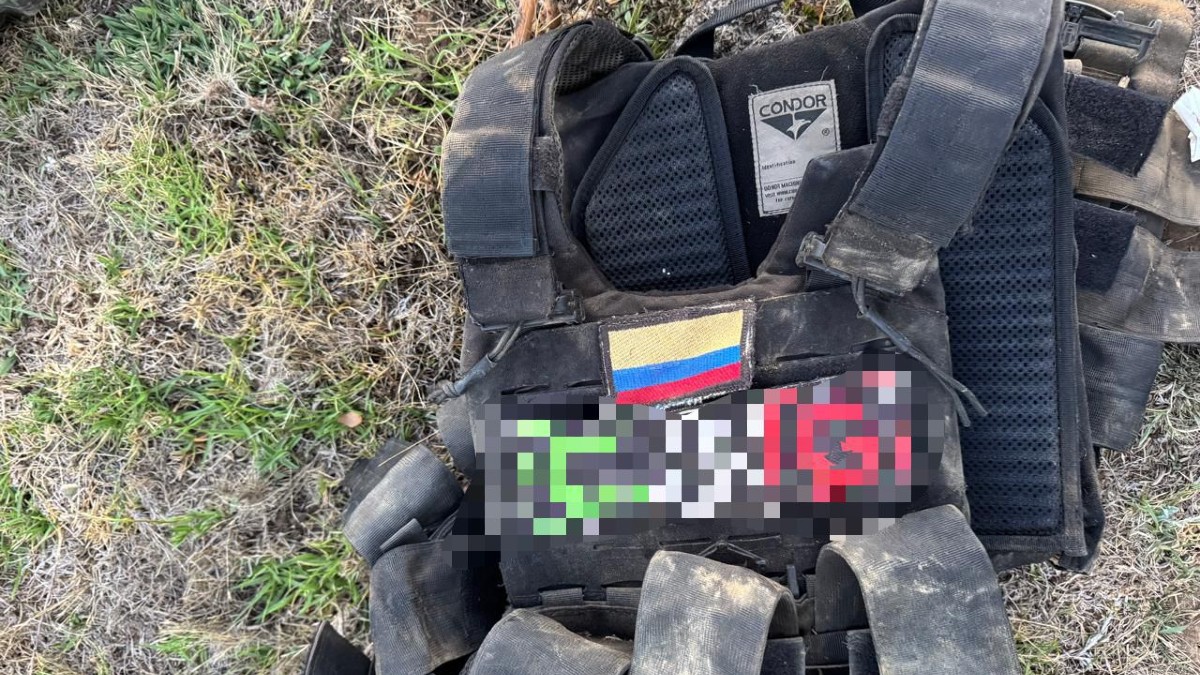 Chaleco táctico con insignia del CJNG censurado con recuadros y la bandera de Colombia tendido sobre el pasto