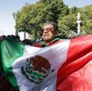 Hombre ondeando la bandera de México en el zócalo de la ciudad de Puebla.