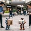 Un hombre y una mujer controlando a dos robots con controles en una plaza comercial