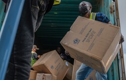 Varias personas descargan un envío de más de 15 toneladas de suministros donados por UNICEF como parte de la respuesta al brote de ébola