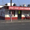 Se observa una fachada de una tienda de abarrotes y el anuncio de Coca Cola.