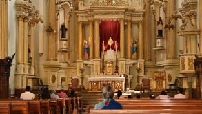 Personas adentro de una iglesia con imágenes religiosas de fondo