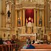 Personas adentro de una iglesia con imágenes religiosas de fondo
