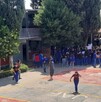Se observa a varios jóvenes que están parados en un patio de una escuela; traen uniforme.