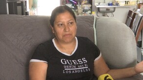 Señora con playera negras con letras guess y micrófono de canal 6