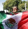 Hombre ondeando la bandera de México en el zócalo de la ciudad de Puebla.