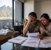 Una pareja revisa documentos sentados frente a una mesa. De fondo se observa el cerro de la silla. Ambos fueron víctimas de fraude inmobiliario en Monterrey.