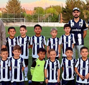 Se observa a muchos niños con uniforme en colores azul y blanco y a dos hombres a los costados.