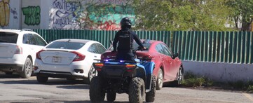 Hombre montando cuatrimoto con uniforme de la Policía