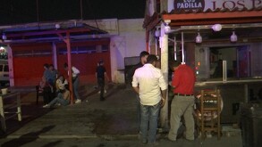 Se observa a varias personas afuera de un establecimiento; es de noche.