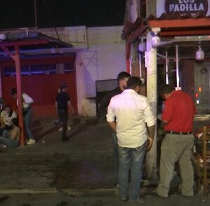 Se observa a varias personas afuera de un establecimiento; es de noche.