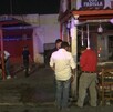Se observa a varias personas afuera de un establecimiento; es de noche.