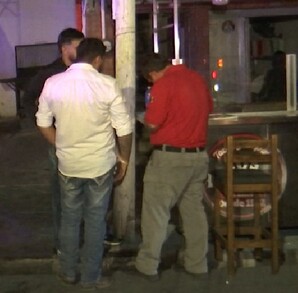 Se observa a varias personas afuera de un establecimiento; es de noche.