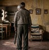 Se observa un padre canoso y una persona de frente que trae un bate de béisbol en las manos.