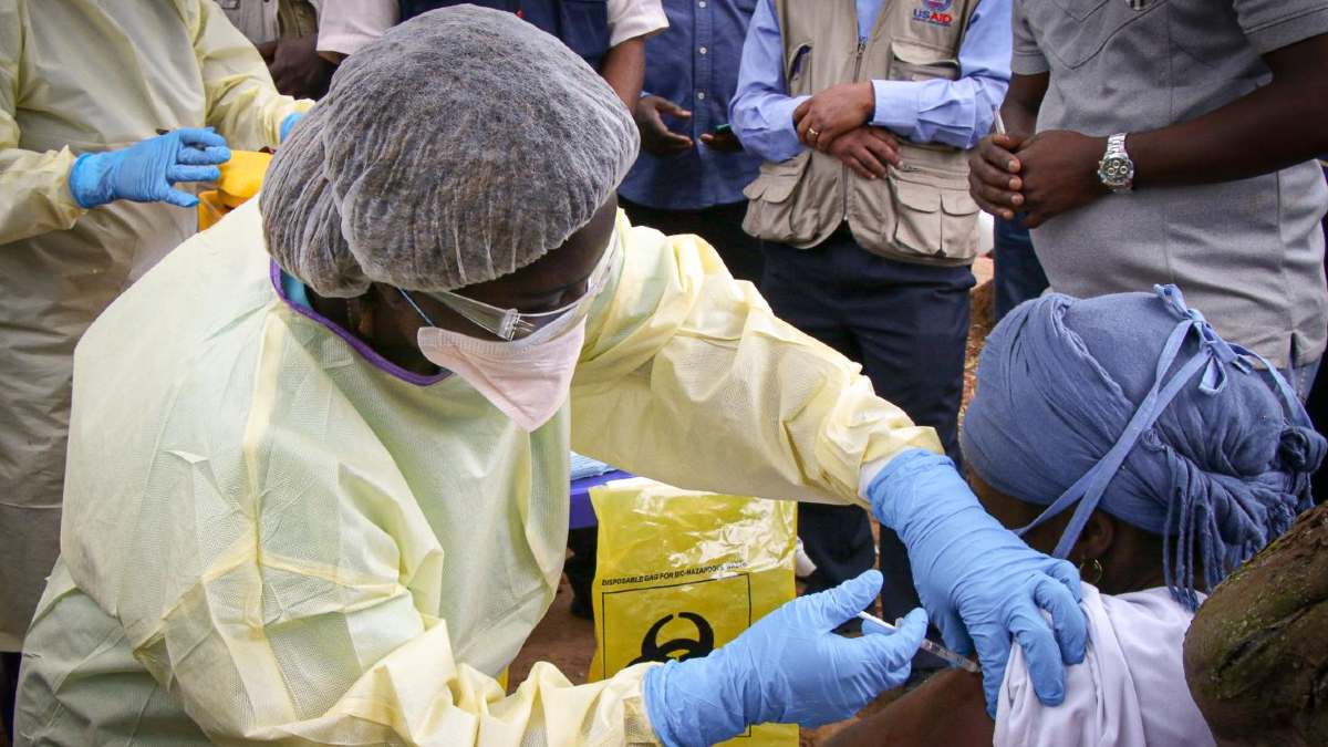 Personal médico con cubrebocas aplicando una vacuna contra el ébola a una persona en Guinea