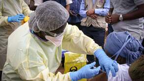 Personal médico con cubrebocas aplicando una vacuna contra el ébola a una persona en Guinea
