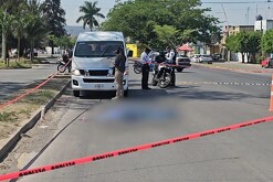 Motos y agentes de la Policía Vial y del IJCF en un área acordonada con una camioneta blanca y un cuerpo cubierto por una manta azul