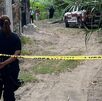 Mujer policía cuida un área asegurada con cinta amarilla.