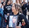 una mujer llorando sostiene una fotografía de su hija en un velorio