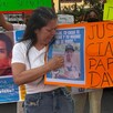 Madre de David Genaro Escalante Reyes durante protesta con carteles y fotos de su hijo desaparecido en calles de Guadalajara