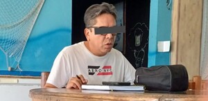 Hombre sentado en una mesa de madera y con los ojos tapados.