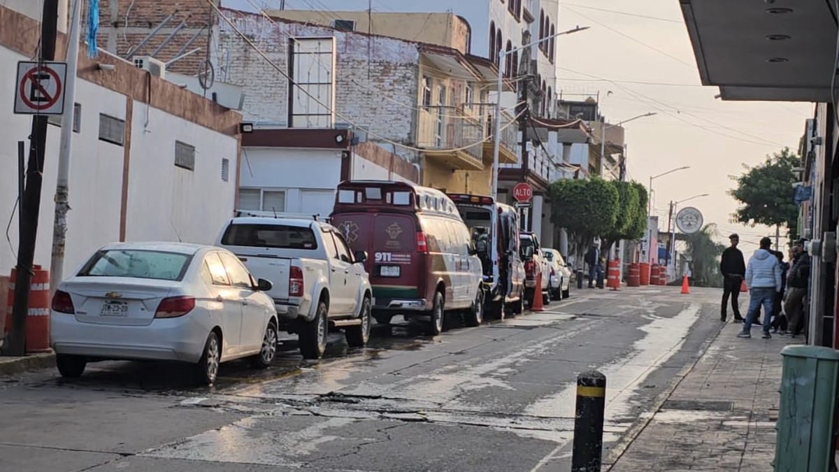 Autos y dos ambulancias estacionadas en calles de El Salto dentro del fraccionamiento Las Lilas con un grupo de personas a un lado