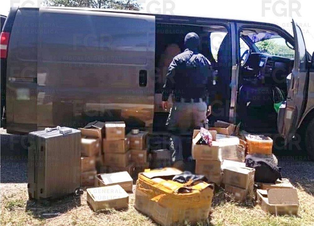 Policía revisa una camioneta con varias cajas de cartón en su interior.