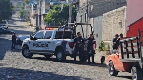 Policías de Tlaquepaque sosteniendo armas largas alrededor de dos patrullas y una camioneta en sitio donde hallaron un cuerpo