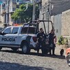 Policías de Tlaquepaque sosteniendo armas largas alrededor de dos patrullas y una camioneta en sitio donde hallaron un cuerpo