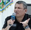 Hombre serio hablando ante un micrófono con la mano estirada.