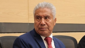 Hombre anciano vestido de traje mirando hacia un costado.