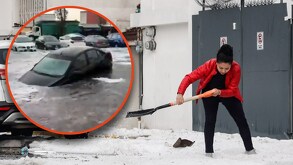 Mujer barriendo la acumulación de granizo en su vivienda junto a un auto flotando en una inundación.