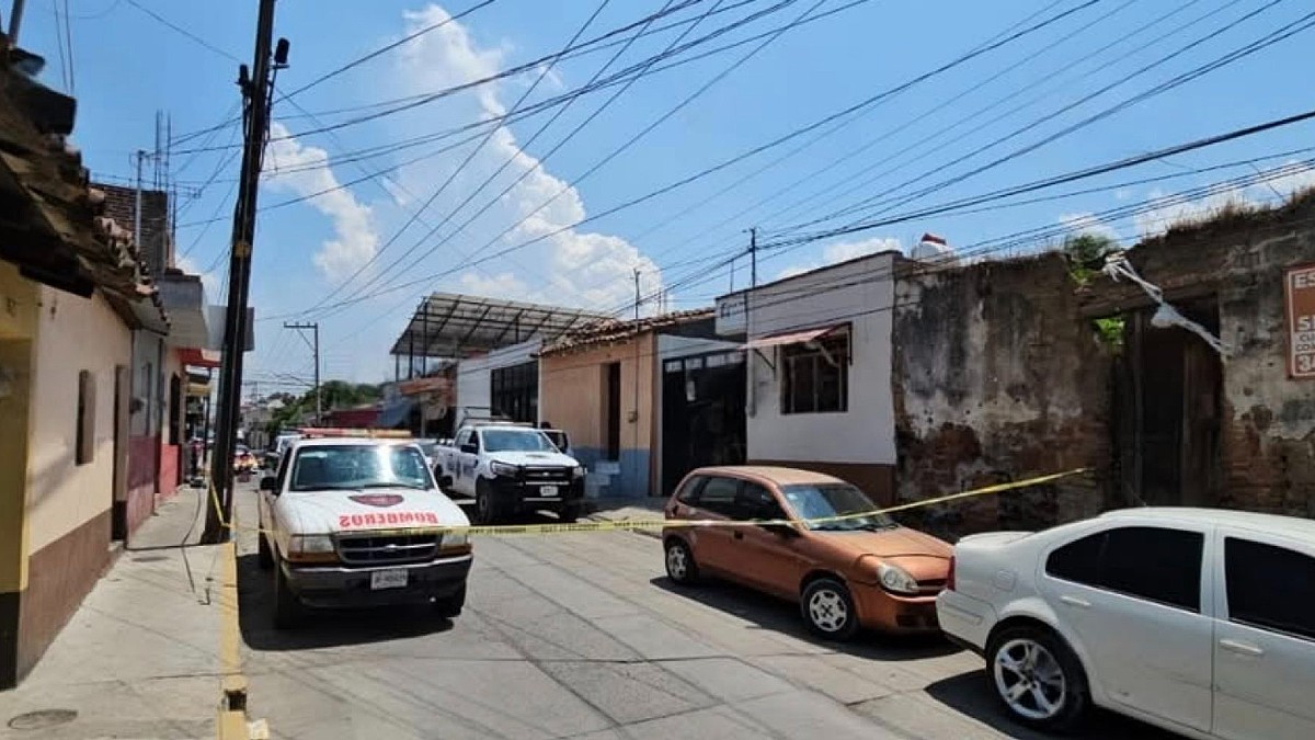 Calle acordonada con una cinta policiaca con vehículos de Protección Civil y la Policía de Zapotiltic estacionados al exterior de una vivienda