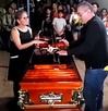Personas en un funeral con el féretro al centro.