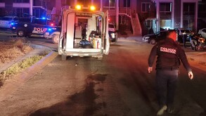 Oficial de la Policía de Tonalá caminando hacia una ambulancia con las puertas abiertas y una patrulla municipal estacionada delante de casas