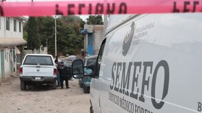 Cinta de seguridad roja junto a un vehículo del Semefo estacionado en Puebla.