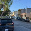Se observa una cinta amarilla de precaución, unas viviendas y unos carros estacionados.