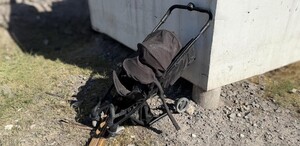Se observa una carriola negra destruida en una zona de piedras.