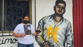 una mujer sostiene un pastel frente a un mural dedicado a misael romero sombrerero
