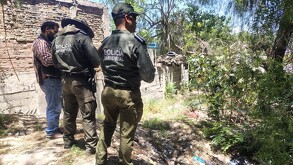 Se observa a tres personas que están con uniforme y de pie sobre una zona donde hay hierbas.