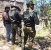Se observa a tres personas que están con uniforme y de pie sobre una zona donde hay hierbas.