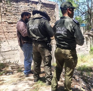 Se observa a tres personas que están con uniforme y de pie sobre una zona donde hay hierbas.