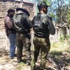 Se observa a tres personas que están con uniforme y de pie sobre una zona donde hay hierbas.