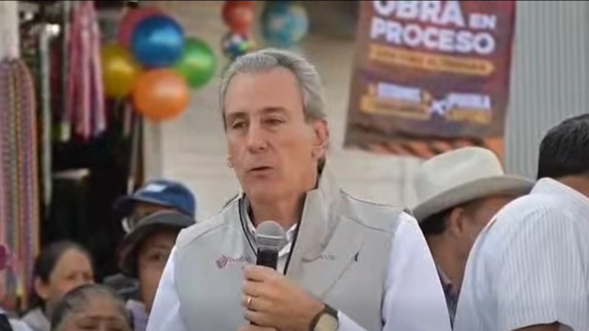 Pepe Chedraui con el micrófono en la mano, de fondo una lona con la leyenda obra en proceso