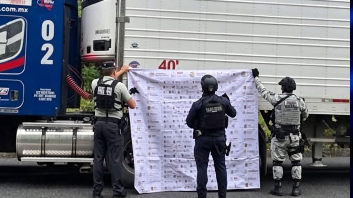 Policías soteniendo una manta junto a un tráiler recuperado.