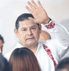 Hombre de camisa blanca alzando la mano junto a una multitud de personas.