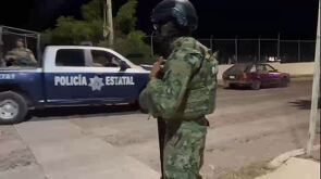 Militar de la Secretaría de Marina con una patrulla de la Policía del Estado de Colima pasando a un costado con policías a bordo