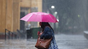 Se observa a una mujer que trae un paraguas en las manos, ya que está lloviendo.