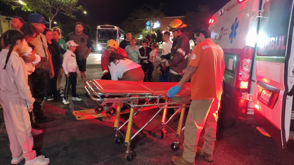 Paramédicos de la Cruz Verde Ignacio Allende y bomberos con una camilla al lado de una ambulancia con un grupo de personas alrededor en medio de la calle