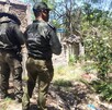 Se observa a tres personas que están con uniforme y de pie sobre una zona donde hay hierbas.